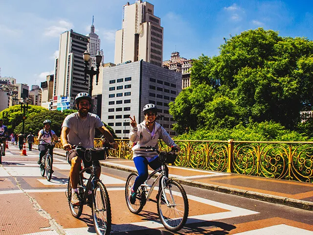 People cycling beside trees and city buildings in Sao Paulo