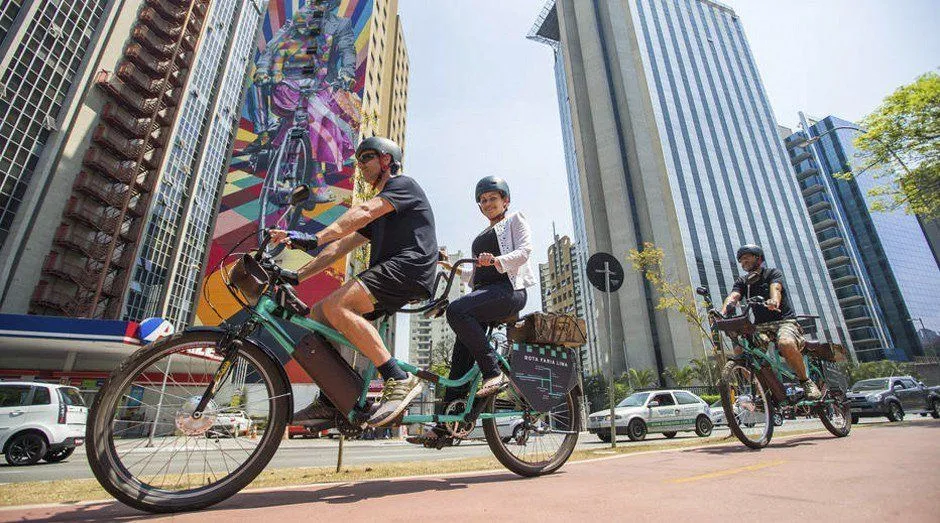 People sharing a tandem bicycle and cycling along an urban cycle lane